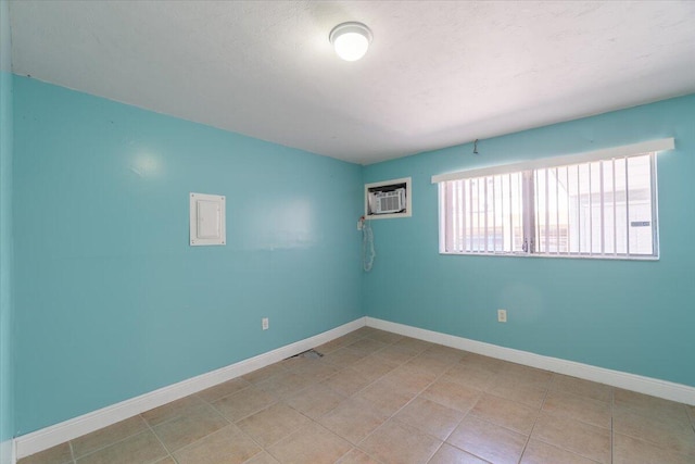 unfurnished room featuring light tile patterned floors, an AC wall unit, and baseboards