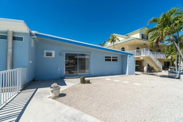 rear view of house featuring stairway, a patio area, and stucco siding