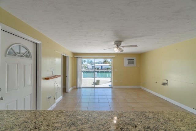 unfurnished room featuring ceiling fan, a textured ceiling, light tile patterned flooring, and a wall unit AC