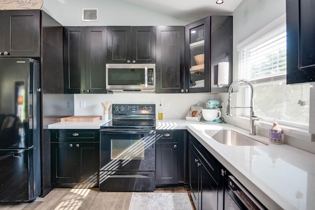 kitchen featuring visible vents, black appliances, a sink, light countertops, and lofted ceiling