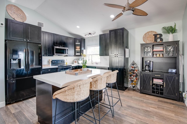 kitchen with visible vents, a kitchen bar, black appliances, lofted ceiling, and ceiling fan