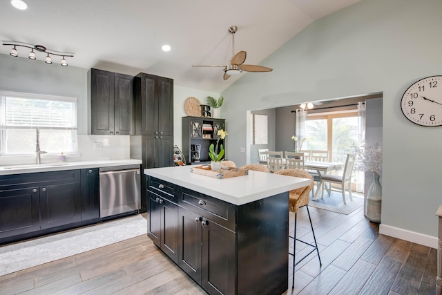 kitchen with dishwasher, a breakfast bar area, light wood-style floors, a ceiling fan, and a sink