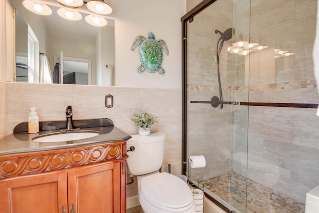 bathroom featuring vanity, tile walls, toilet, and a stall shower