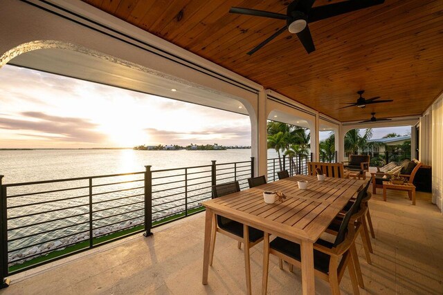 patio terrace at dusk with a water view and ceiling fan