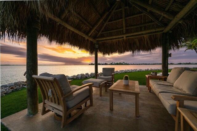 patio terrace at dusk with a water view, an outdoor living space, and a gazebo