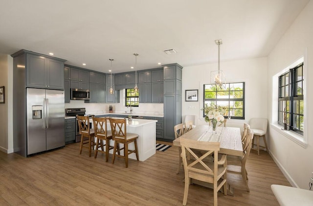 dining space with sink, light hardwood / wood-style flooring, and a chandelier