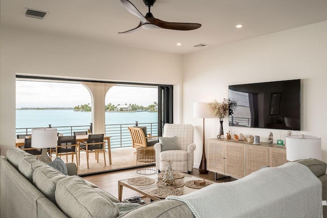 living room with hardwood / wood-style floors, ceiling fan, and a water view