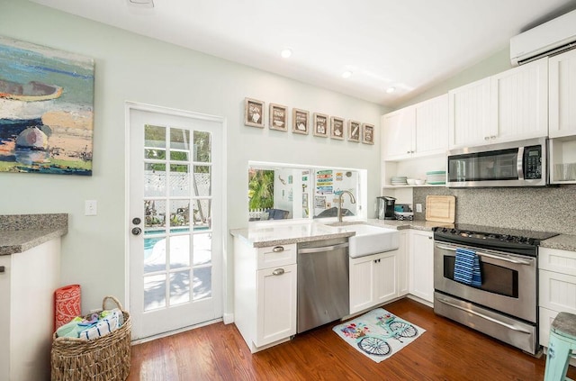 421 United St, Key West, FL 33040 - kitchen featuring tasteful backsplash, a wall mounted air conditioner, appliances with stainless steel finishes, dark hardwood / wood-style flooring, and white cabinets