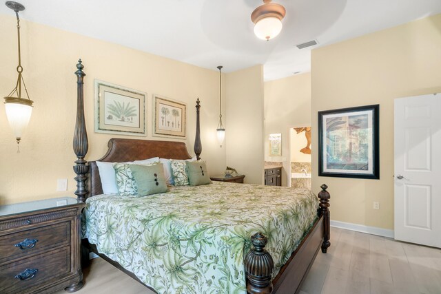 bedroom with ceiling fan, ensuite bath, and light hardwood / wood-style flooring