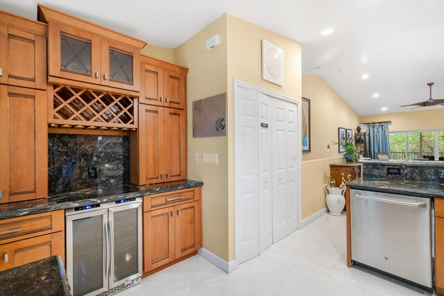 kitchen with lofted ceiling, stainless steel dishwasher, beverage cooler, and dark stone counters