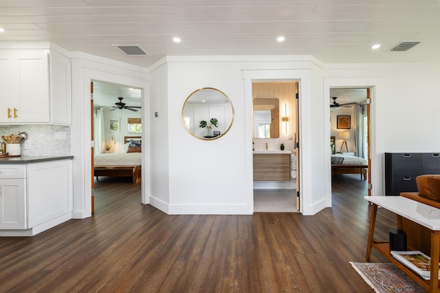 corridor featuring dark wood-style floors, visible vents, baseboards, recessed lighting, and crown molding