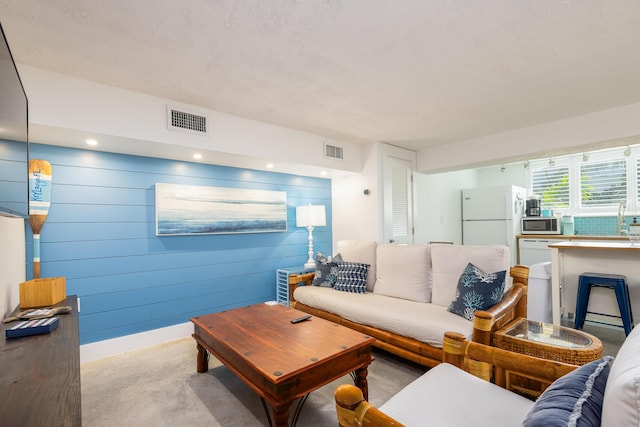 living room with recessed lighting, visible vents, and wooden walls