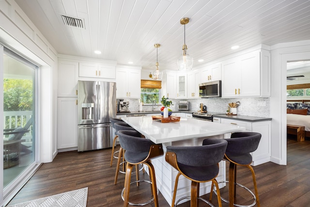 kitchen featuring decorative backsplash, appliances with stainless steel finishes, dark wood-style floors, white cabinets, and a sink