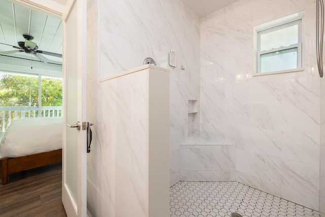 full bath featuring a wealth of natural light, connected bathroom, ceiling fan, and a tile shower