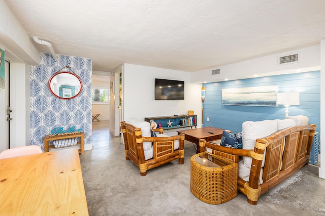 living room featuring visible vents, a textured ceiling, and concrete floors