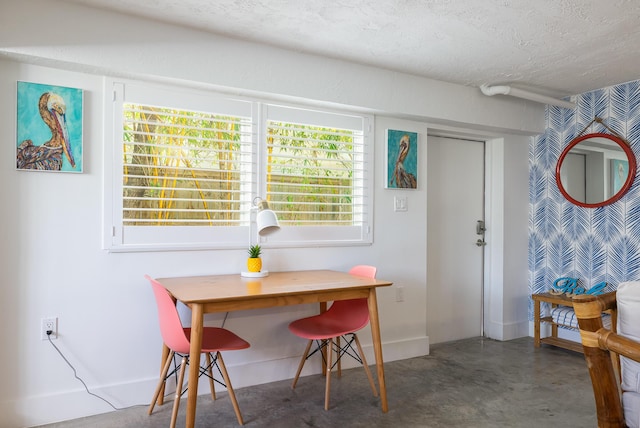 dining space featuring a textured ceiling, baseboards, and finished concrete floors