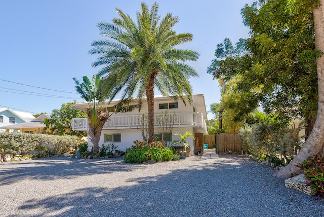 exterior space featuring stucco siding, a balcony, and fence