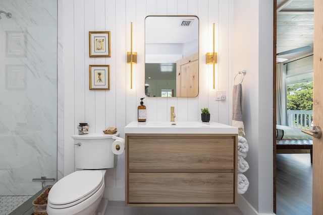 bathroom featuring a marble finish shower, toilet, and vanity