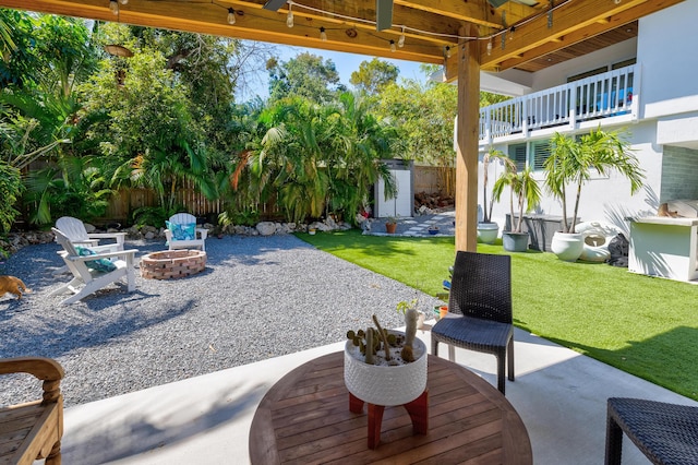 view of patio with an outbuilding, a fire pit, a storage shed, and fence