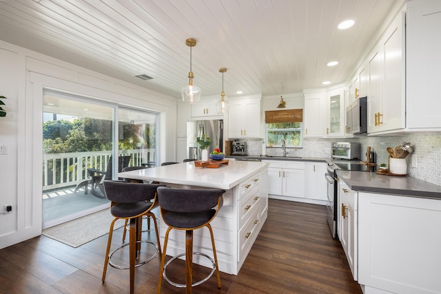 kitchen with decorative backsplash, white cabinets, a kitchen breakfast bar, and stainless steel appliances