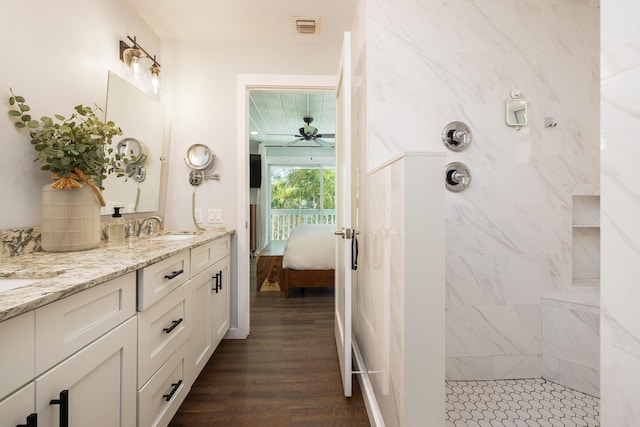 ensuite bathroom with vanity, wood finished floors, visible vents, a ceiling fan, and a walk in shower