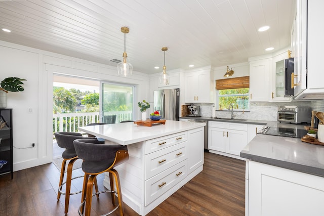 kitchen with a sink, tasteful backsplash, dark wood finished floors, white cabinetry, and stainless steel appliances