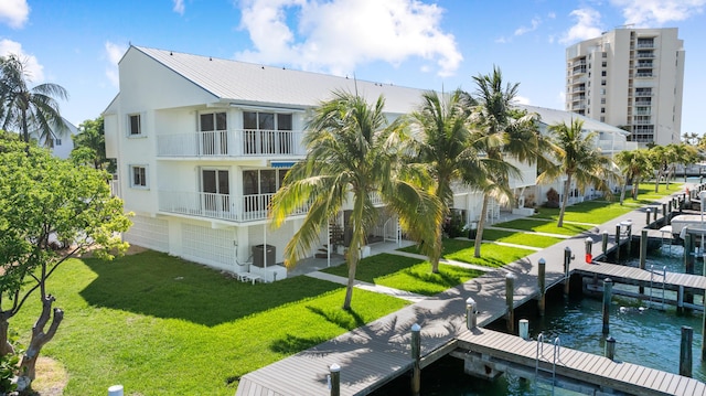 95 Coco Plum Dr Unit 1A, Marathon, FL 33050 - rear view of house featuring stucco siding, a lawn, a water view, a balcony, and a metal roof