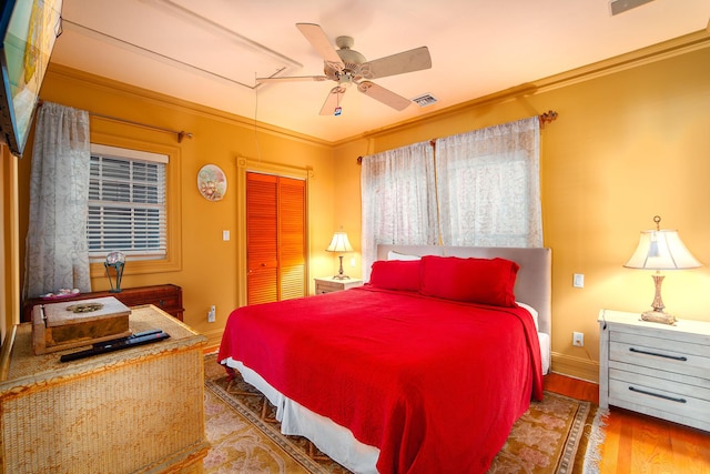 bedroom featuring hardwood / wood-style floors, crown molding, a closet, and ceiling fan