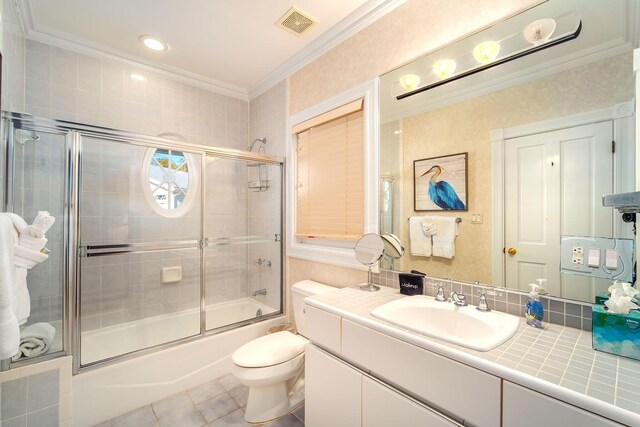 full bathroom with tile patterned floors, toilet, bath / shower combo with glass door, ornamental molding, and vanity