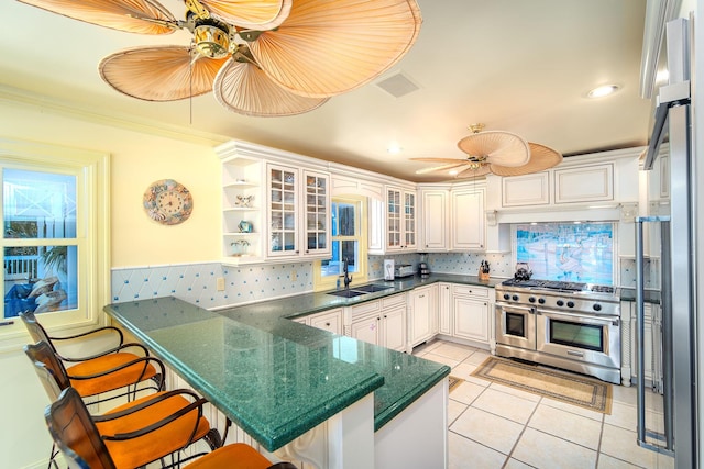 kitchen with sink, a breakfast bar area, white cabinetry, double oven range, and kitchen peninsula