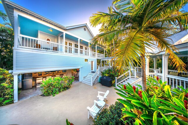 back house at dusk with a balcony and a patio area