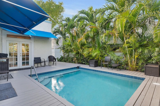 view of pool with french doors and a deck