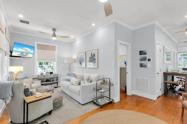 living area featuring plenty of natural light, a ceiling fan, visible vents, and wood finished floors