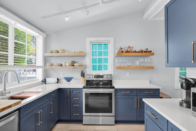 kitchen with a sink, open shelves, track lighting, light countertops, and appliances with stainless steel finishes