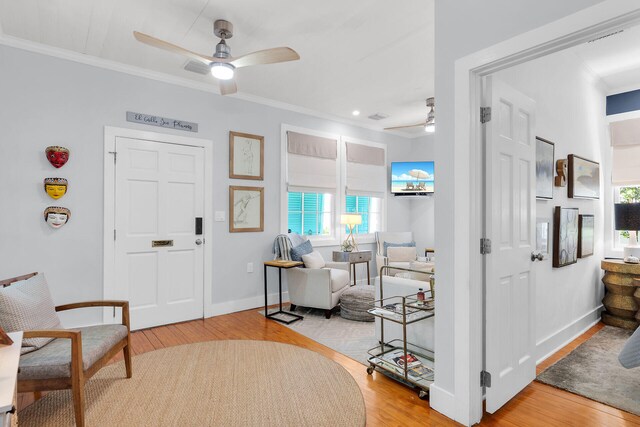 entryway featuring a ceiling fan, ornamental molding, a healthy amount of sunlight, and wood finished floors