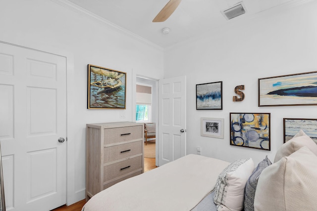 bedroom featuring visible vents, wood finished floors, a ceiling fan, and ornamental molding
