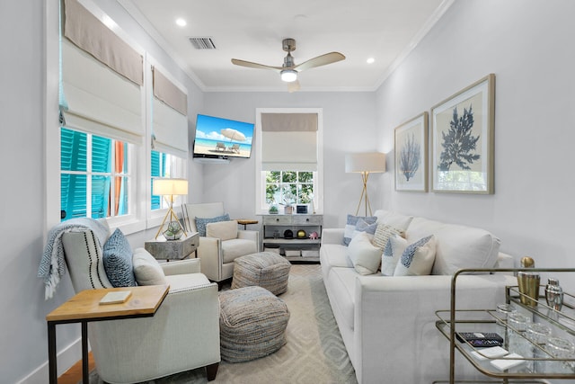 living area featuring crown molding, visible vents, and a ceiling fan