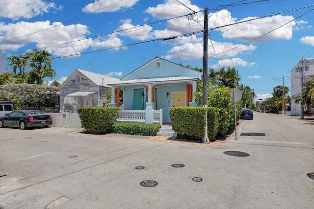 bungalow featuring covered porch, fence, and metal roof
