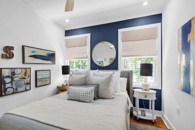 bedroom featuring ornamental molding, wood finished floors, baseboards, and multiple windows