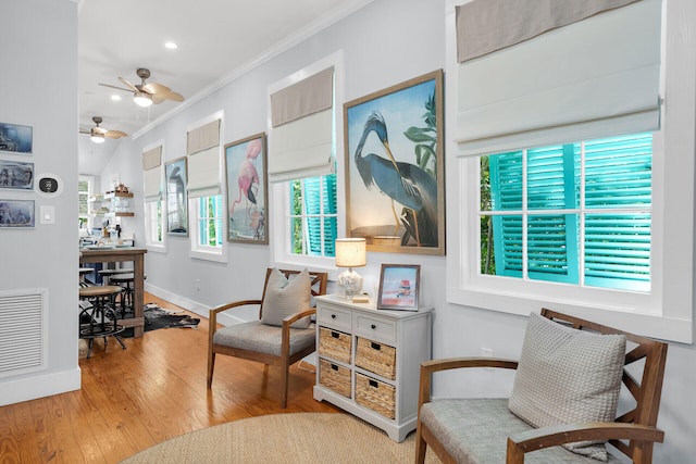 sitting room featuring wood finished floors, visible vents, crown molding, ceiling fan, and baseboards