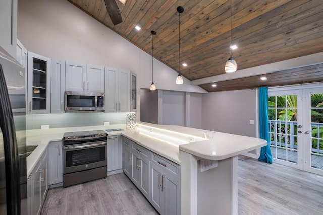 kitchen featuring tasteful backsplash, stainless steel appliances, decorative light fixtures, and kitchen peninsula