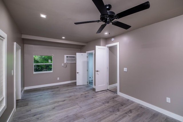 unfurnished bedroom featuring an AC wall unit, ceiling fan, and light wood-type flooring