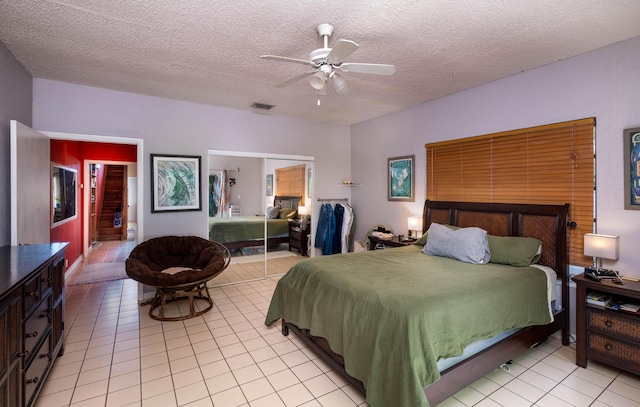 tiled bedroom with ceiling fan, a closet, and a textured ceiling