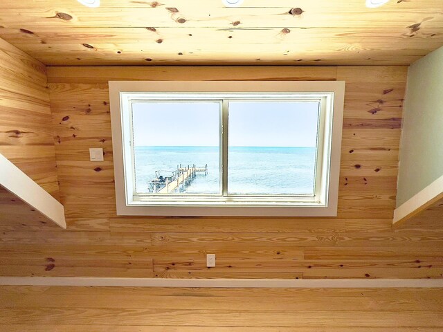 interior details featuring a water view, wooden ceiling, and wooden walls