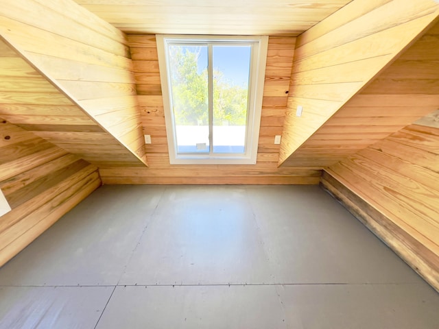 bonus room featuring concrete floors, wood ceiling, and wood walls