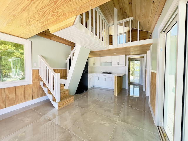 stairway featuring wood ceiling, high vaulted ceiling, and wood walls