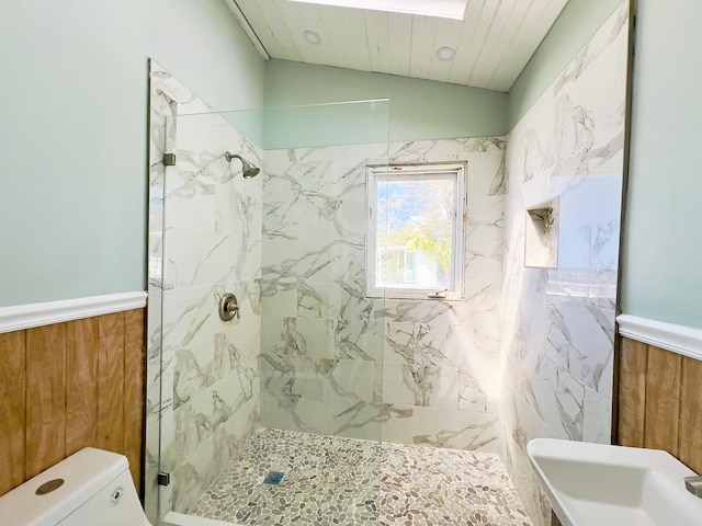 bathroom with a tile shower, lofted ceiling, toilet, and wood walls