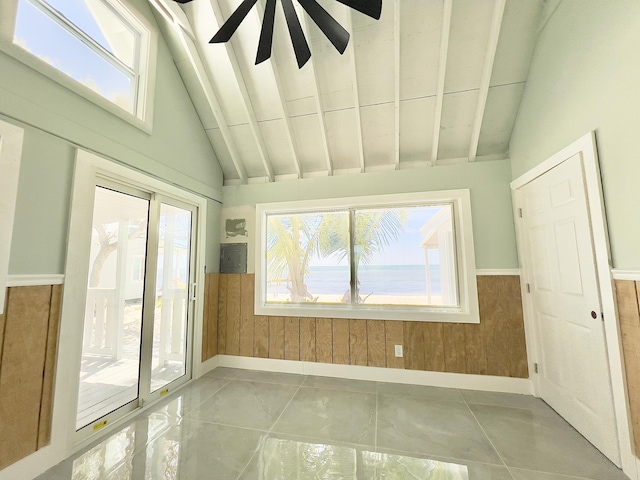 tiled empty room featuring a healthy amount of sunlight and lofted ceiling with beams