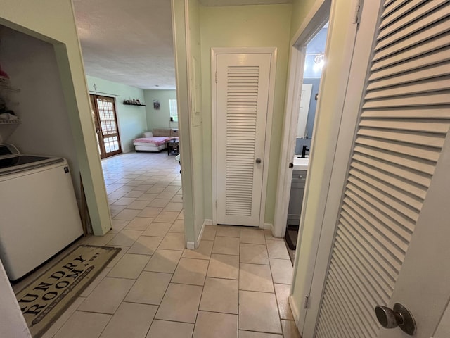 hallway with light tile patterned flooring and washer / dryer