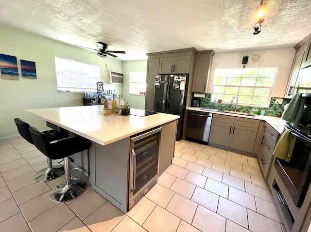 kitchen with sink, gray cabinetry, a kitchen breakfast bar, wine cooler, and stainless steel dishwasher